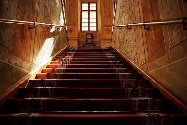 Zabytkowe schody pokryte wejściem z czerwonego dywanu w starym pałacu