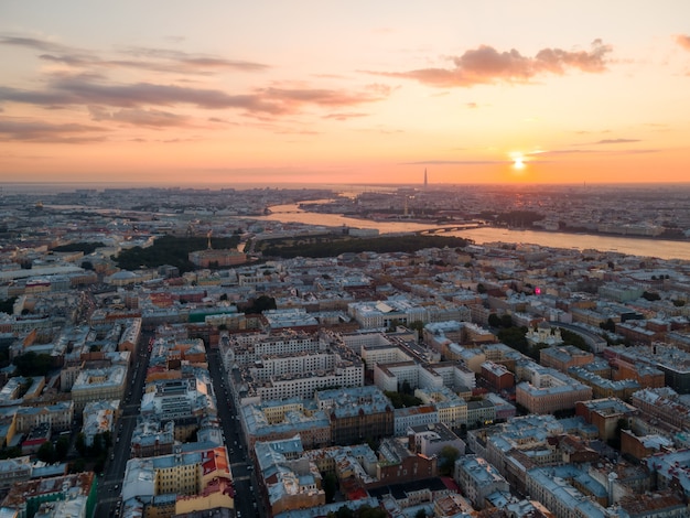Zachmurzony pomarańczowy zachód słońca nad Sankt Petersburgiem, Rosja. Zdjęcie lotnicze z drona. Stare domy mieszkalne i Newy na ziemi. Wieżowiec na tle. Koncepcja wędrówki.