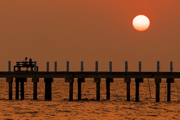 Zachód słońca i most na środku morza z kochankami