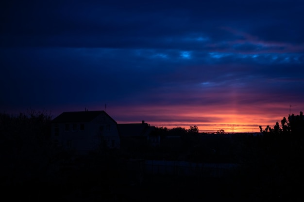 Zachód słońca na niebie Sylwetki domów i drzew Kolory wieczornych chmur Ukraińska przyroda