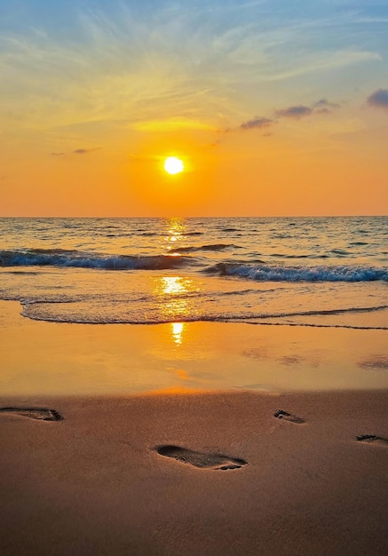 Zachód słońca na plaży ze śladami stóp na piasku