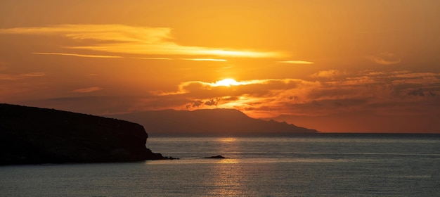 Zachód słońca nad grecką wyspą Cyklady Grecja Złote słońce chowa się za chmurą Sparkle sea Banner
