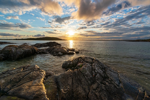 Zachód słońca nad horyzontem oceanu w ciepły wieczór lata w pobliżu nieba drogowego w Connemara.