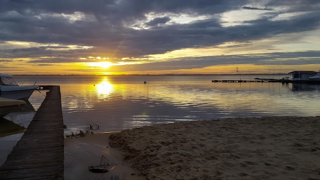 Zachód słońca nad jeziorem sanguinet o wschodzie słońca z piaszczystą plażą i drewnianym pontonem w landes france