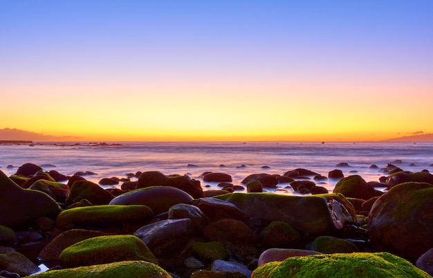 Zachód słońca nad oceanem i wielkie omszałe kamienie -- Sunset seascape