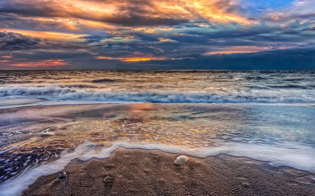 zachód słońca nad oceanem z plażą i falą uderzającą w niego