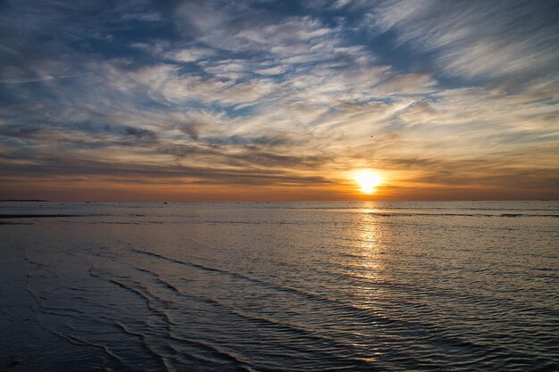 Zachód słońca oświetlone morze Piaszczysta plaża na pierwszym planie Światłe fale Morza Bałtyckiego.