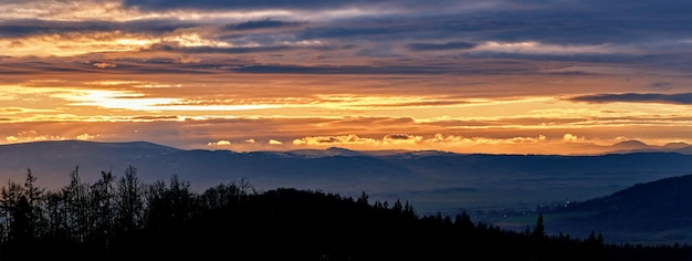 Zachód słońca z dramatycznym pochmurnym niebem nad górami kształtuje piękny krajobraz przyrody
