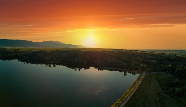 Zachodzące słońce oświetla sylwetki pól bałkańskich gór i widok z góry panoramy jeziora