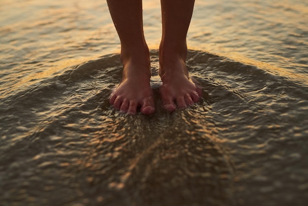 Zachowaj spokój i zmocz stopy Przycięte zdjęcie kobiety stojącej ze stopami w wodzie