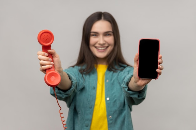 Zachwycona uśmiechnięta kobieta trzymająca telefon w stylu retro i telefon komórkowy wybierz najlepsze urządzenie dla siebie