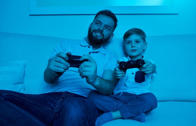 Zachwycony ojciec i syn grają w domu w gry wideo