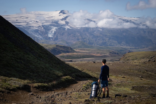 Zadek wysokiego kaukaskiego turystow, stojącego ponad górami i mgłą na szlaku turystycznym Laugavegur. Islandia.