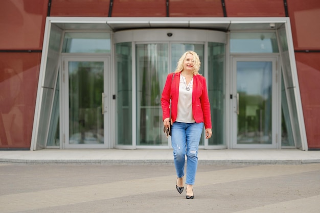 Zadowolona kobieta w średnim wieku wychodzi z banku lub biurowca