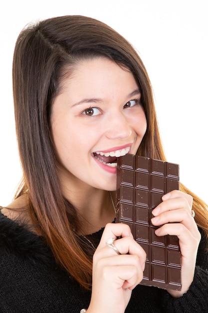 Zadowolona ładna dziewczyna gryząca tabliczkę czekolady uśmiechnięta