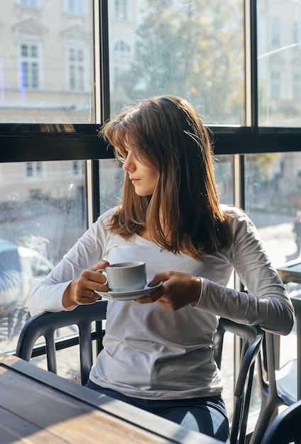 Zadowolona młoda biznesowa kobieta cieszyć się przerwą na kawę, w kawiarni.