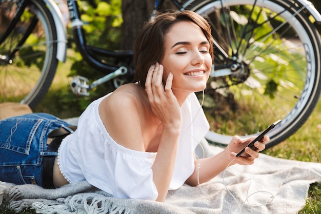 Zadowolona młoda dziewczyna, słuchanie muzyki z telefonu komórkowego