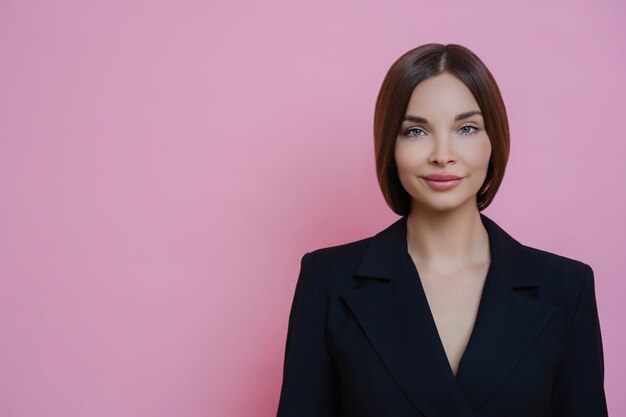 Zadowolona młoda kobieta w formalnym stroju spokojna ekspresja pozuje na różowym tle miejsce na reklamy