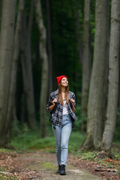 Zadowolona młoda turystka ma niezwykłą wycieczkę pieszą, która nosi plecak podczas spaceru po zielonym tle przyrody