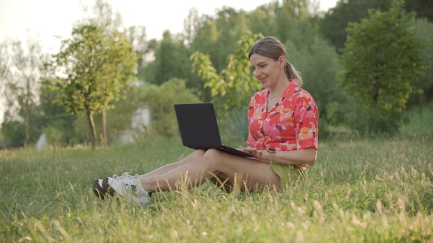 Zadowolona uśmiechnięta kobieta patrzy na ekran laptopa