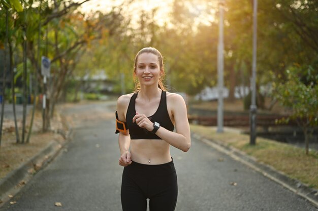 Zadowolona wysportowana kobieta w odzieży sportowej biegająca w parku publicznym Zdrowy styl życia sportowa koncepcja odnowy biologicznej