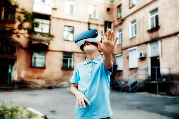 Zafascynowany mały chłopiec za pomocą gogli wirtualnej rzeczywistości VR. na wolnym powietrzu