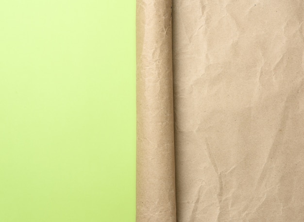 Zagięty róg rolki brązowego papieru na zielonym tle, miejsce na napis