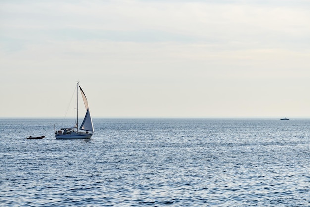 Żaglówki w pięknym spokojnym morzu, jasne tło błękitnego nieba, poziomy seascape z żaglówkami rybackimi. Żeglarstwo w wietrzny dzień. Krajobraz Morza Bałtyckiego, aktywne wakacje, letnia przygoda