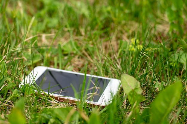 Zdjęcie zagubiony smartfon leży w zielonej trawie w wiosenny dzień
