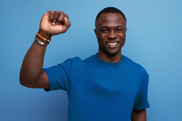 Zainspirowany młody inteligentny Amerykanin w koszulce gestykuluje rękami na niebieskim tle z miejsca na kopię