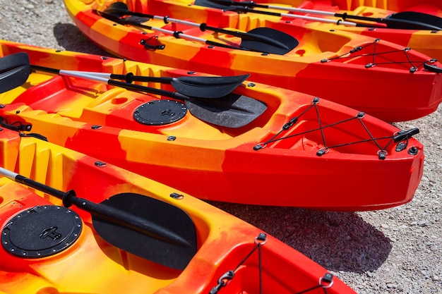 Zajęcia rekreacyjne, sportowe, kajaki. Łódź do raftingu. Na piaszczystej plaży jest kilka jasnopomarańczowych kajaków.