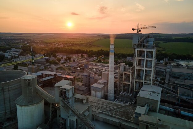 Zakład cementowy z wysoką strukturą fabryczną i dźwigami wieżowymi w obszarze produkcji przemysłowej Koncepcja produkcji i globalnego przemysłu