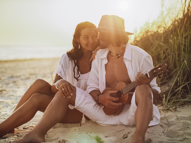 Zakochana para gra na gitarze i odpoczywa na plaży