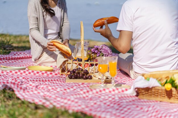 Zakochana para korzystających z czasu pikniku w parku na zewnątrz Piknik szczęśliwej pary relaksującej wraz z koszykiem piknikowym
