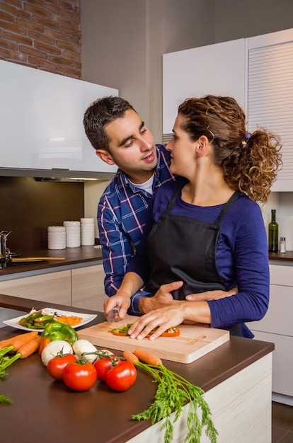 Zakochana para przytulanie i przygotowywanie zdrowych warzyw w kuchni. Koncepcja nowoczesnego stylu życia rodziny.