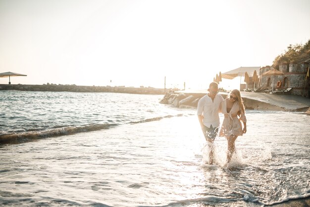 Zdjęcie zakochana para spaceruje po plaży w pobliżu morza. młoda rodzina o zachodzie słońca nad morzem śródziemnym. koncepcja wakacji letnich