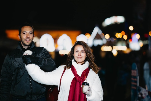 Zakochana para w świątecznym mieście z noworocznymi światłami w zimowy wieczór. Małżonkowie w zimowym zakrzepie