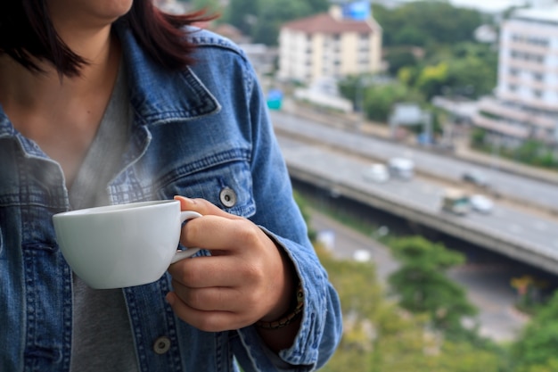 Zakończenie kobiety ręki chwyta filiżanki i odgórnego widoku pejzaż miejski