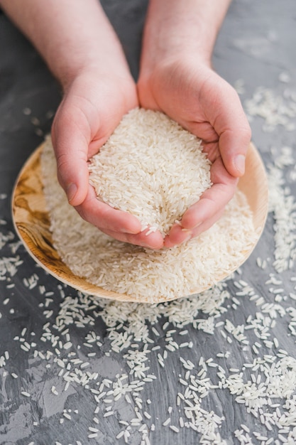 Zdjęcie zakończenie ludzka ręka trzyma adra niegotowany biały jaśminowy ryż