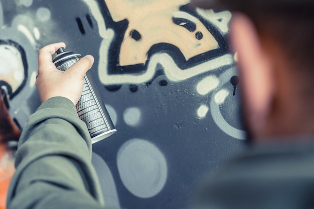 Zdjęcie zakończenie mężczyzna ręki opryskiwania farba na graffiti ścianie