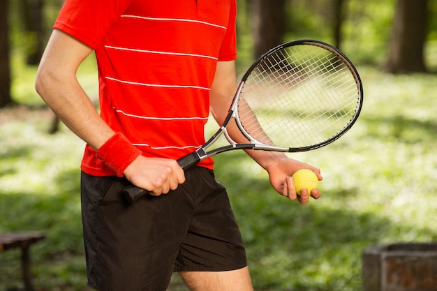 Zakończenie mężczyzna ręki up trzyma tenisową piłkę i kant na zielonym tle.