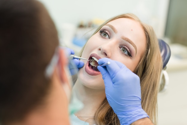 Zakończenie obrazek młodej kobiety obsiadanie w dentysty krześle z otwartym usta przy dentysty biurem podczas gdy mieć egzamin.