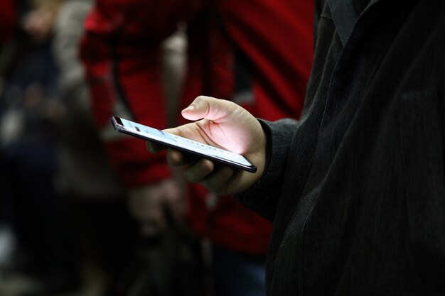 Zdjęcie zakończenie osoby ręki mienia telefon komórkowy z światło ekranem. człowiek przewija wiadomości lub gra. zabij czas i rozrywkę w koncepcji transportu publicznego