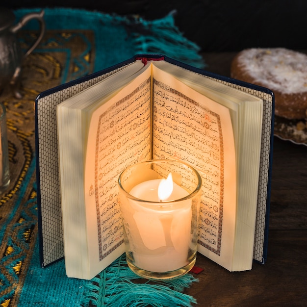 Zakończenie płonąca świeczka blisko rozpieczętowanego koranu