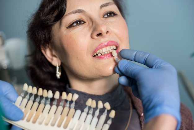 Zakończenie portret kobieta w stomatologicznym kliniki biurze. Dentysta sprawdza i wybiera kolor zębów, wykonując proces leczenia. Stomatologia