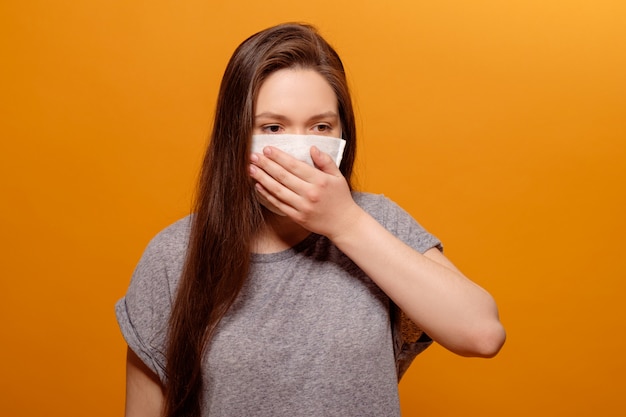 Zakończenie portret młoda kobieta kicha na żółtej pomarańcze w ochronnej medycznej maski coronavirus pandemii