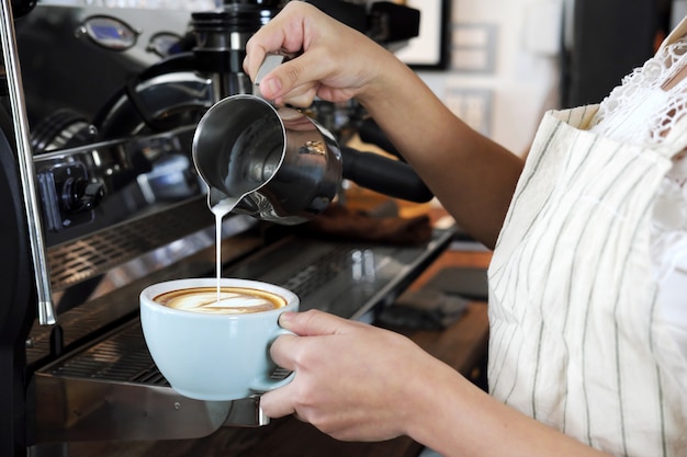 Zakończenie ręka robi latte lub cappucino kawie w sklep z kawą barista