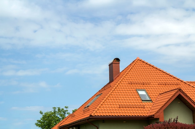 Zakończenie szczegół nowy nowożytny domu wierzchołek z gontowym czerwonym dachem, wysokim kominem, poddasza okno na jasnym niebieskim niebie