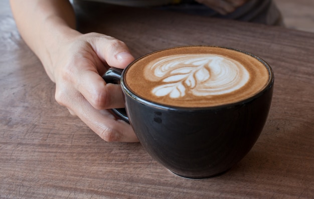 Zakończenie up filiżanka gorąca latte sztuki kawa na drewnianym stole