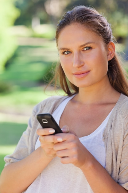 Zakończenie up kobieta trzyma jej telefon komórkowego w parku